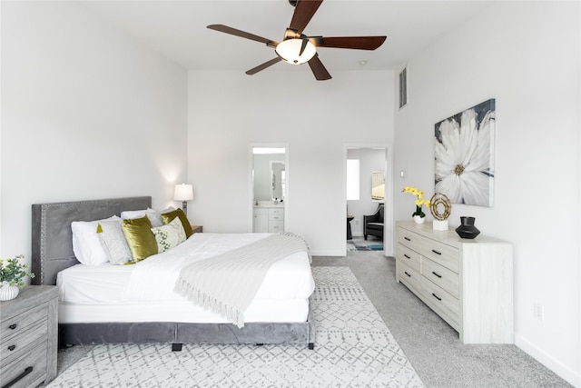 bedroom featuring light colored carpet, high vaulted ceiling, a ceiling fan, ensuite bathroom, and baseboards