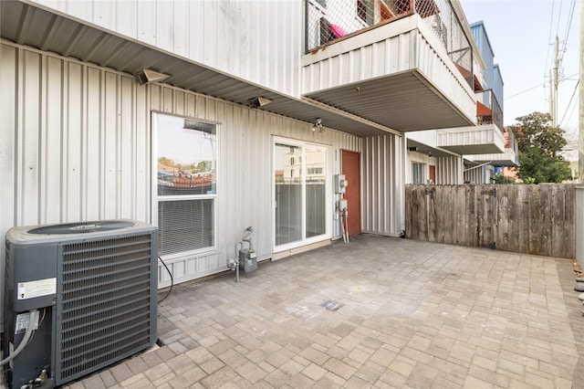 view of patio / terrace featuring central AC, fence, and a balcony
