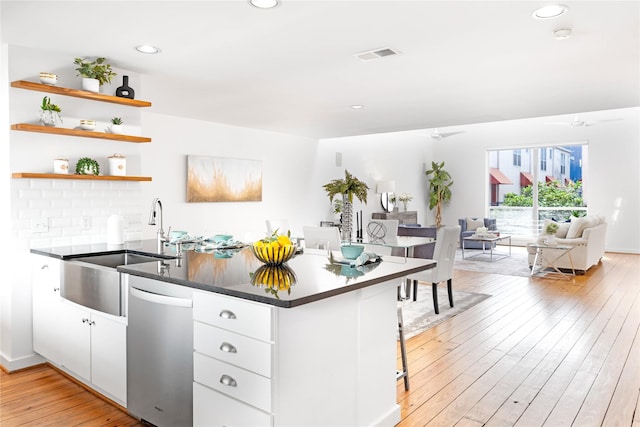 kitchen with dishwasher, a peninsula, light wood-style flooring, open floor plan, and white cabinetry