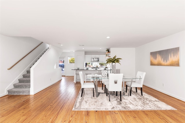 dining space with stairway, light wood finished floors, baseboards, and recessed lighting