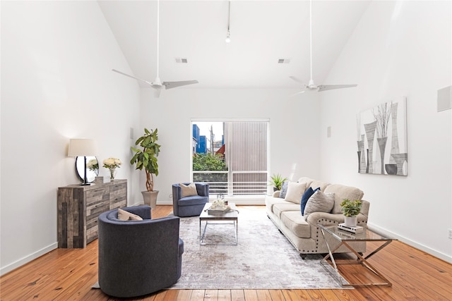 living area with high vaulted ceiling, a ceiling fan, hardwood / wood-style flooring, and baseboards