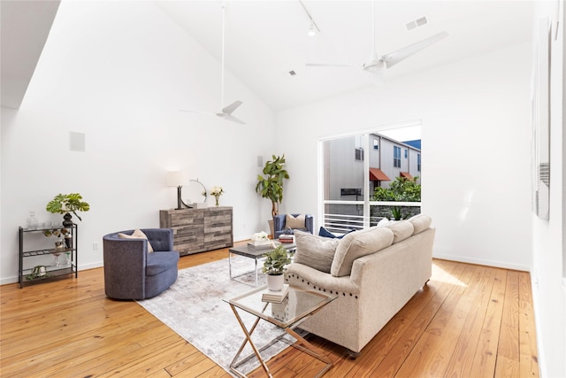 living area featuring ceiling fan, high vaulted ceiling, wood-type flooring, baseboards, and rail lighting