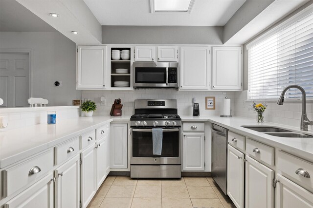 kitchen with appliances with stainless steel finishes, a sink, backsplash, and white cabinets