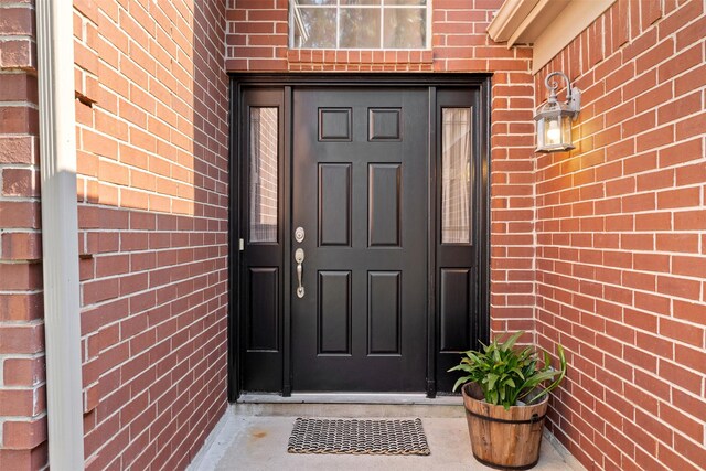 view of exterior entry featuring brick siding