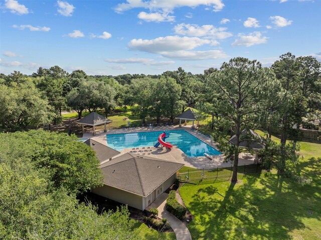 community pool with a gazebo, view of scattered trees, and a patio area
