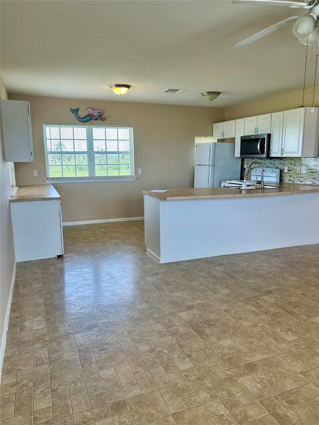 3913 1st, Galveston, TX 77554 - kitchen with freestanding refrigerator, stainless steel microwave, baseboards, and white cabinets