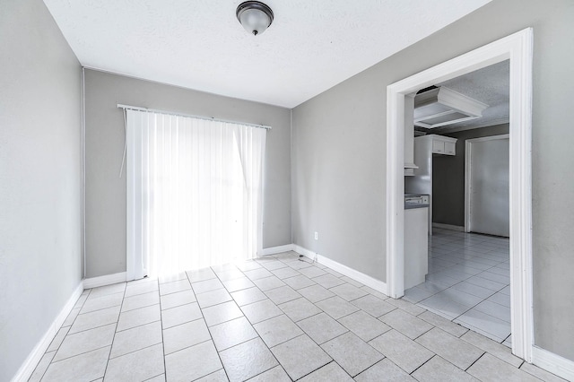 spare room with light tile patterned floors, a textured ceiling, and baseboards