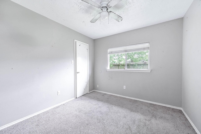 carpeted spare room with a ceiling fan, baseboards, and a textured ceiling