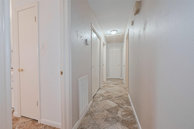 7919 Cabot St, Houston, TX 77078 - hallway featuring attic access, baseboards, and light stone finish floors