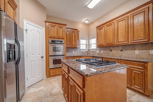 kitchen featuring stainless steel appliances, a center island, stone counters, brown cabinetry, and backsplash