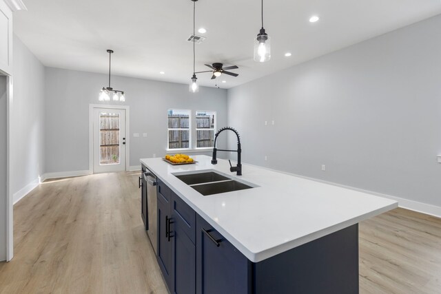 kitchen with a sink, light wood finished floors, recessed lighting, an island with sink, and hanging light fixtures