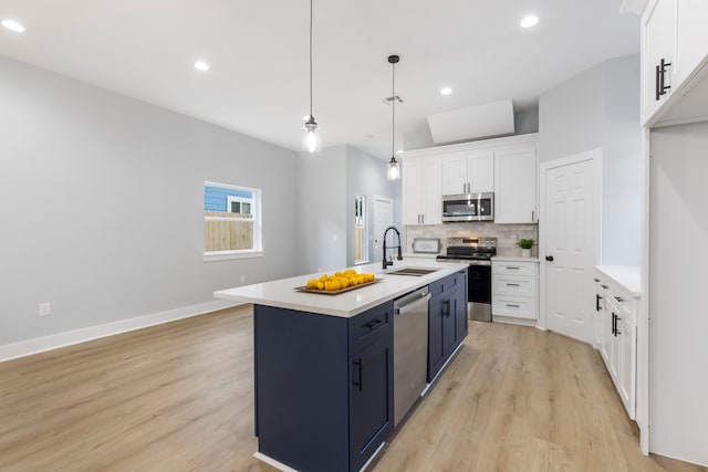 kitchen featuring stainless steel appliances, a sink, tasteful backsplash, light wood-style floors, and white cabinets