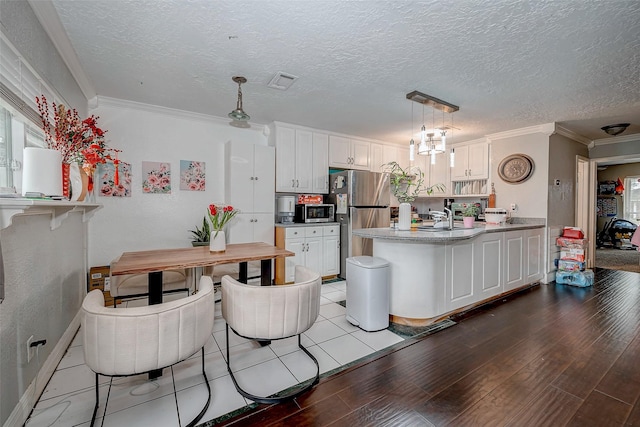 11104 Timber Crest Dr, Houston, TX 77065 - kitchen with appliances with stainless steel finishes, a peninsula, white cabinetry, crown molding, and light wood-style flooring