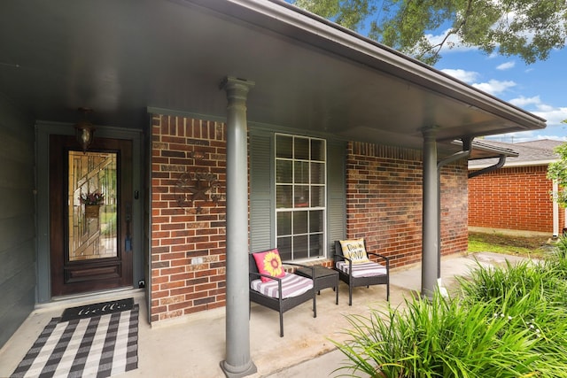entrance to property with a porch and brick siding