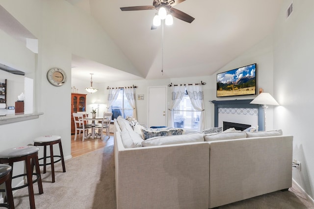 carpeted living room featuring vaulted ceiling, a ceiling fan, and a fireplace