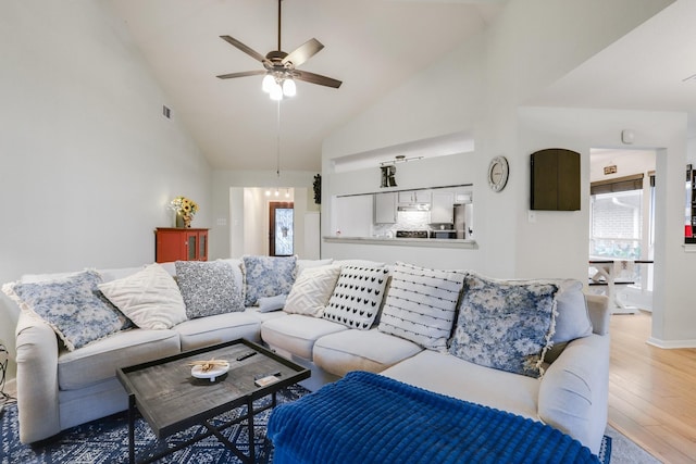 living room featuring wood finished floors, healthy amount of natural light, a ceiling fan, high vaulted ceiling, and baseboards