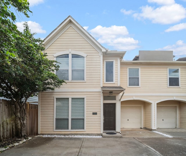 view of property featuring fence, an attached garage, and driveway