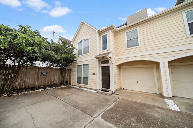 townhome / multi-family property with fence, a garage, driveway, and a chimney
