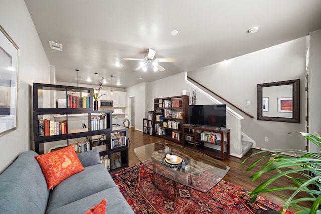 living room with stairs, a ceiling fan, dark wood finished floors, and baseboards