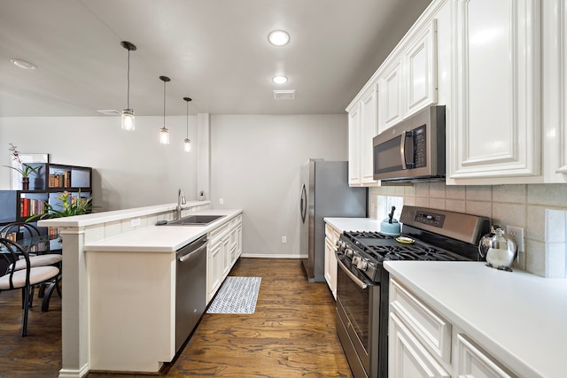 kitchen featuring stainless steel appliances, a sink, a peninsula, dark wood-style flooring, and white cabinets