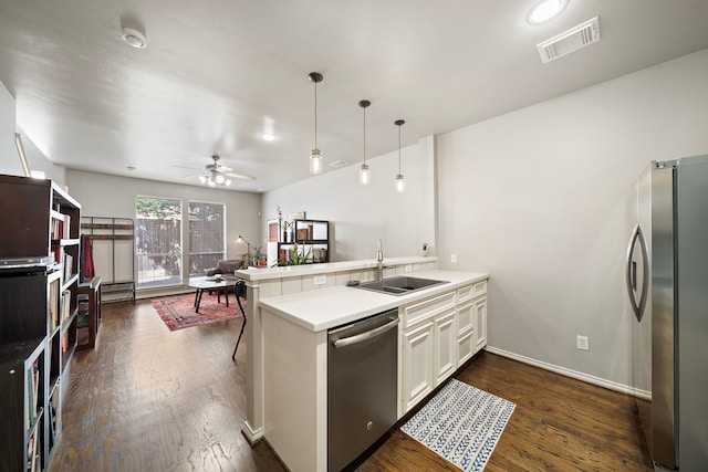 kitchen featuring appliances with stainless steel finishes, a sink, a peninsula, dark wood finished floors, and a ceiling fan