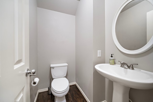 bathroom with wood finished floors, toilet, a sink, and baseboards