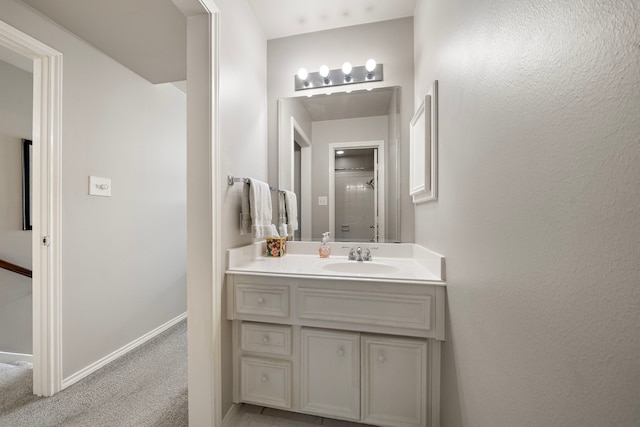 bathroom with a shower with door, vanity, and baseboards