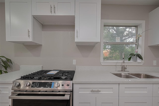 7702 Darnay Dr, Houston, TX 77033 - kitchen with stainless steel range with gas cooktop, a sink, and white cabinets