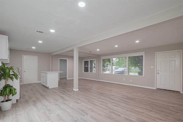 7702 Darnay Dr, Houston, TX 77033 - unfurnished living room with light wood finished floors, baseboards, recessed lighting, and a textured ceiling