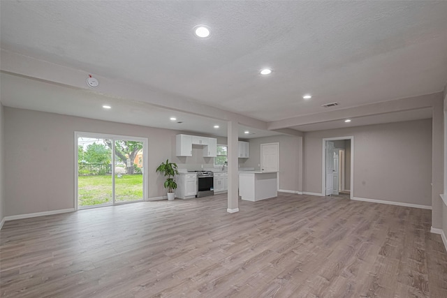 7702 Darnay Dr, Houston, TX 77033 - unfurnished living room featuring baseboards, recessed lighting, light wood-type flooring, and a textured ceiling