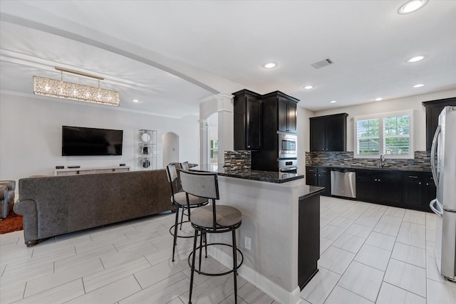 929 Oak St, Houston, TX 77018 - kitchen featuring appliances with stainless steel finishes, open floor plan, arched walkways, a kitchen bar, and decorative backsplash