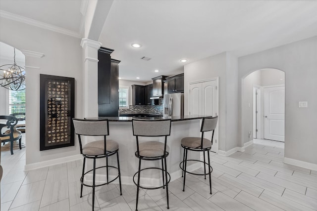 929 Oak St, Houston, TX 77018 - kitchen featuring stainless steel refrigerator with ice dispenser, a kitchen bar, arched walkways, dark countertops, and crown molding