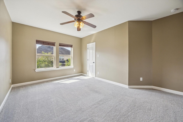 carpeted empty room featuring ceiling fan, baseboards, and a smoke detector