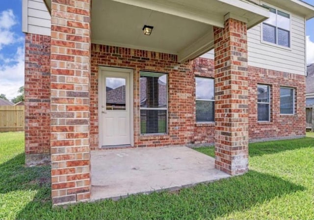view of exterior entry featuring brick siding and a patio area