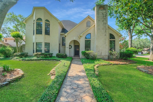view of front of property featuring a front yard, brick siding, and a chimney