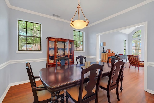 dining space with wood finished floors, crown molding, and baseboards