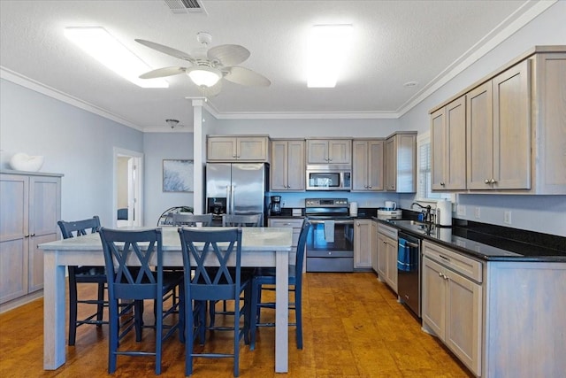 kitchen featuring stainless steel appliances, a sink, crown molding, dark countertops, and a ceiling fan