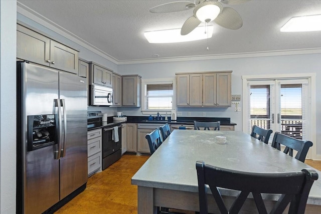 kitchen featuring appliances with stainless steel finishes, crown molding, a sink, a ceiling fan, and dark wood-style flooring