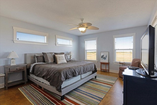 bedroom featuring dark wood-style floors, baseboards, a ceiling fan, and a textured ceiling