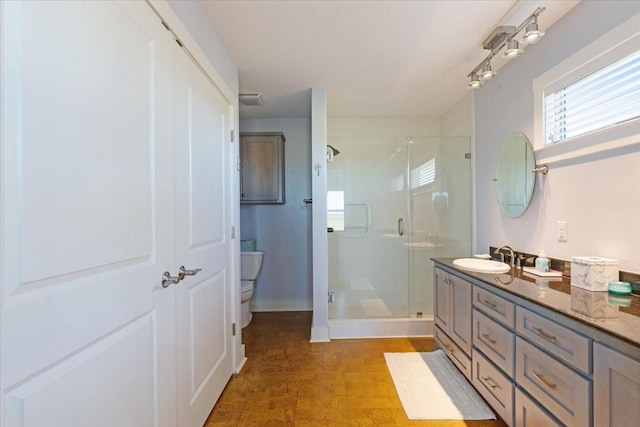 bathroom with a shower stall, toilet, vanity, and baseboards
