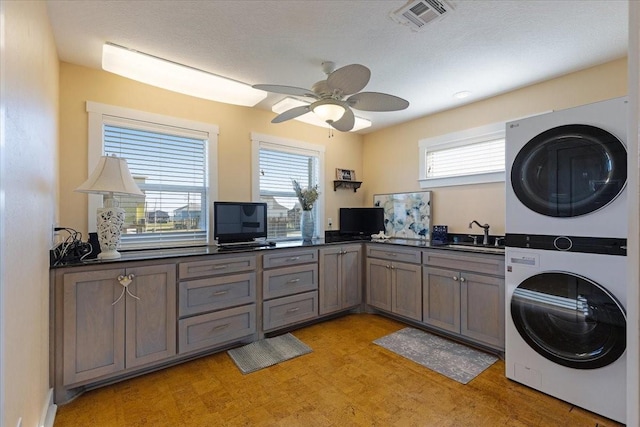 laundry room with stacked washer / drying machine, light wood-type flooring, plenty of natural light, and ceiling fan