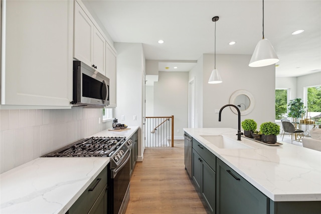 524 Janisch Rd, Houston, TX 77018 - kitchen featuring stainless steel appliances, a sink, light wood finished floors, an island with sink, and white cabinets