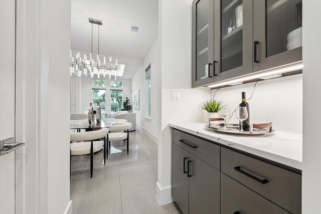bar featuring a chandelier, baseboards, and pendant lighting