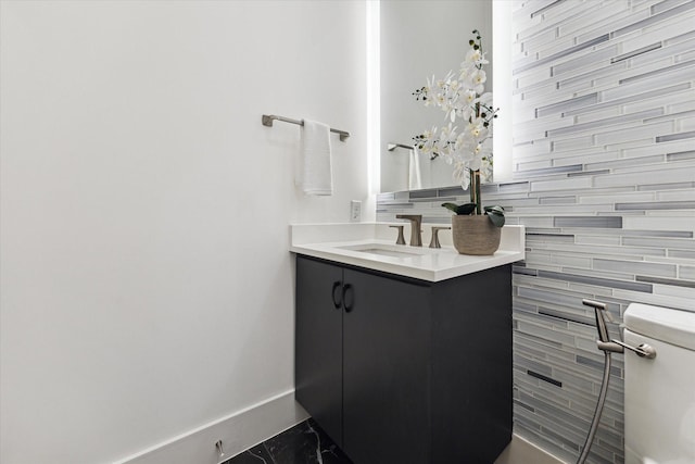 bathroom with baseboards, vanity, toilet, and marble finish flooring