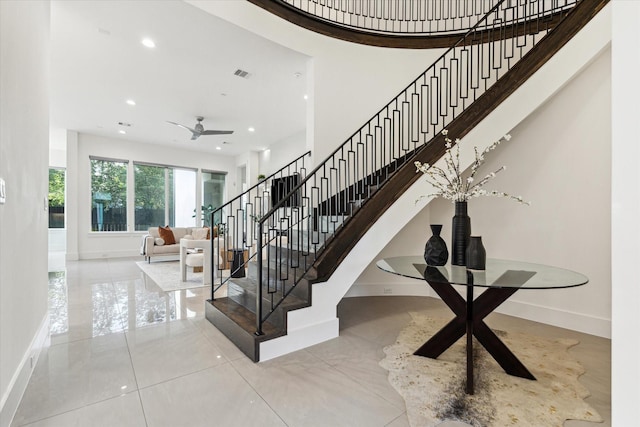 staircase with baseboards, recessed lighting, a towering ceiling, a ceiling fan, and tile patterned floors