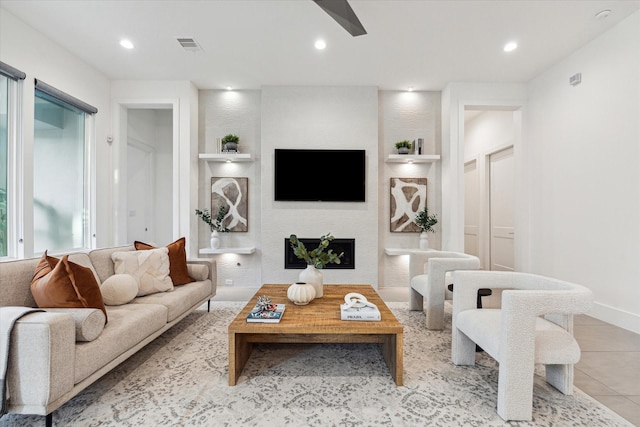 living room with ceiling fan, a fireplace, recessed lighting, and tile patterned flooring