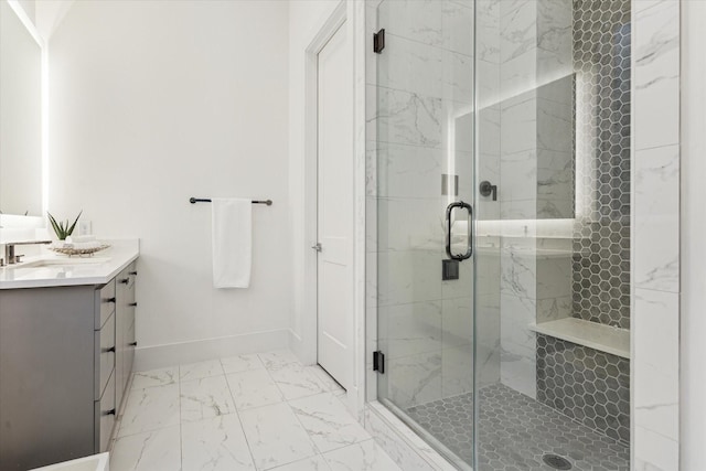 full bathroom with marble look tile flooring, a stall shower, vanity, and baseboards