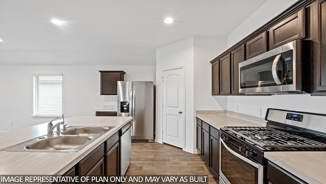 14819 Crimson Peak Ln, Splendora, TX 77372 - kitchen featuring stainless steel appliances, a sink, dark brown cabinetry, light wood finished floors, and light countertops