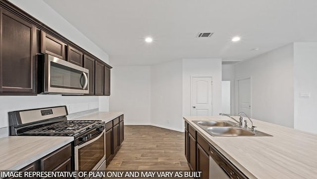 14819 Crimson Peak Ln, Splendora, TX 77372 - kitchen with appliances with stainless steel finishes, a sink, wood finished floors, light countertops, and dark brown cabinetry