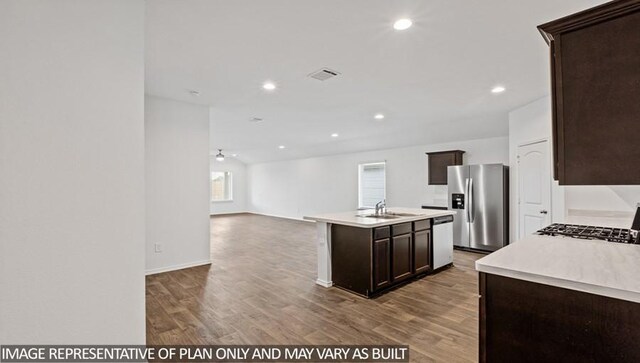14819 Crimson Peak Ln, Splendora, TX 77372 - kitchen featuring stainless steel appliances, light wood-style floors, dark brown cabinets, a kitchen island with sink, and light countertops